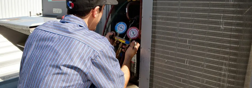 HVAC technician servicing a condenser unit in Milliken